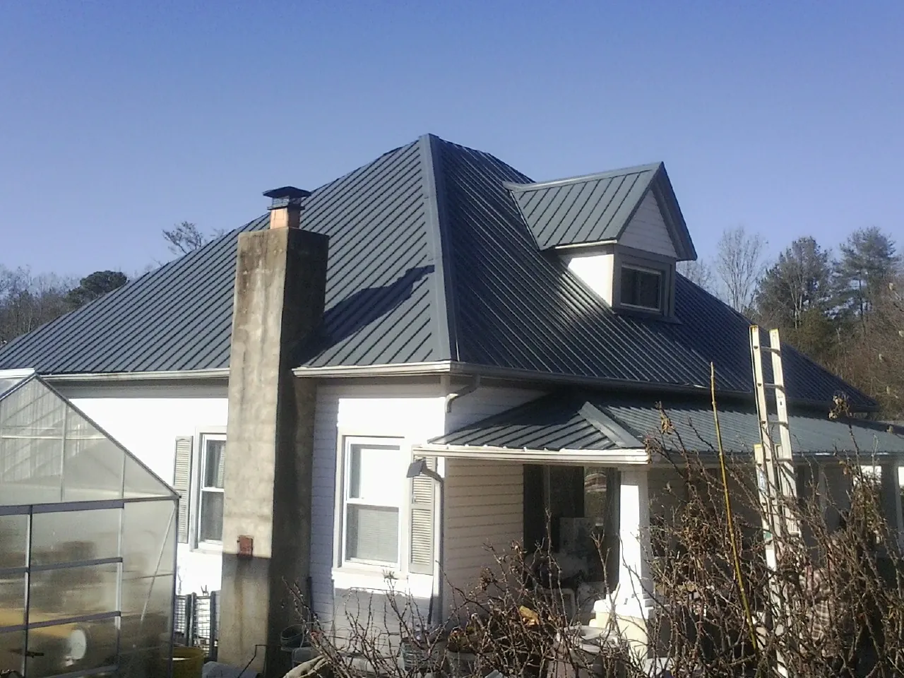 Dark blue standing seam metal roof on a white farmhouse with dormer — Slate & Tile Roof Repair by Roofing Brothers in Pocahontas