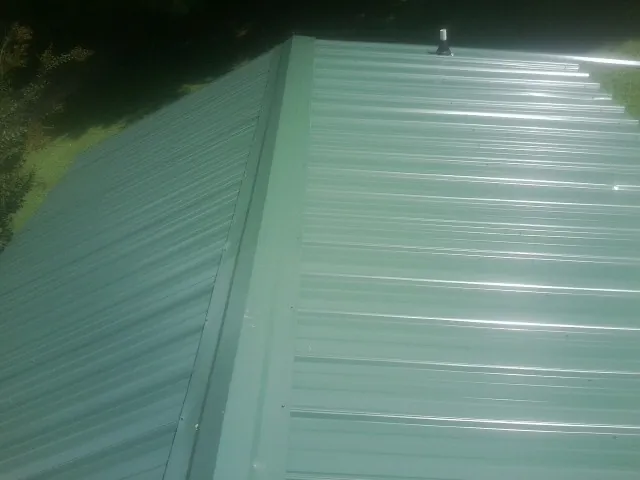 New green metal panels meeting at the ridge of a roof — Flat Roof Repair work by our crew in Pocahontas
