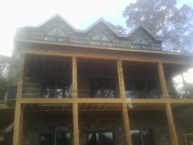 Dormers and porch framing on a large log home under construction — Roof Coating work by our crew in Pocahontas