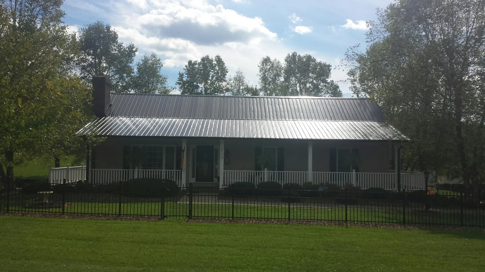Gray metal roof on a brick ranch with a full width front porch — Gutter Guard Installation work by our crew in Pocahontas