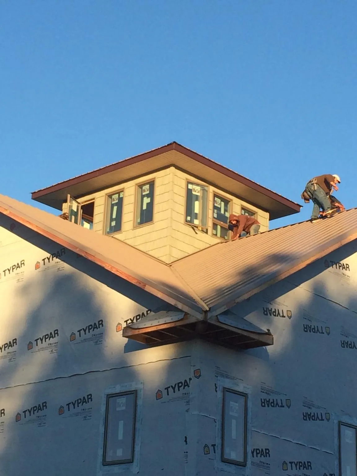 Roofers working around a rooftop cupola on a new metal roof at sunset — Roof Waterproofing in Pocahontas by Roofing Brothers